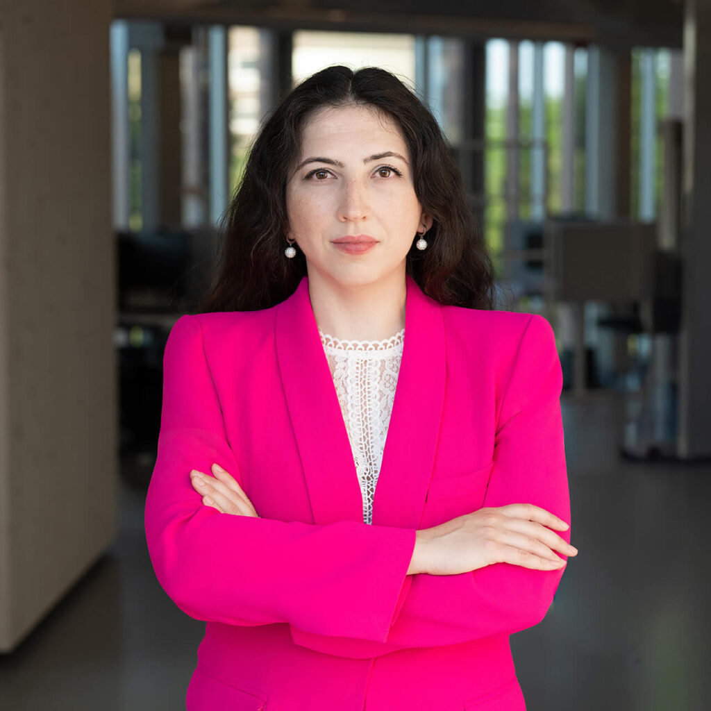 Die Gründerin von Dual Rooms - Dr Julia Tschirka in einem Bürokomplex in einem pinken Blazer und direktem Blick in die Kamera